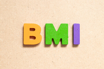 Color alphabet letter in word BMI (abbreviation of body mass index) on wood background