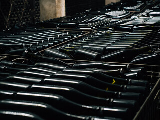 Bottles of wine aging covered with old dust in underground cellar close up.