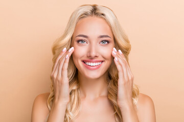 Obraz premium Portrait of attractive cheerful wavy-haired girl washing clear pure skin uplift effect isolated over beige pastel color background