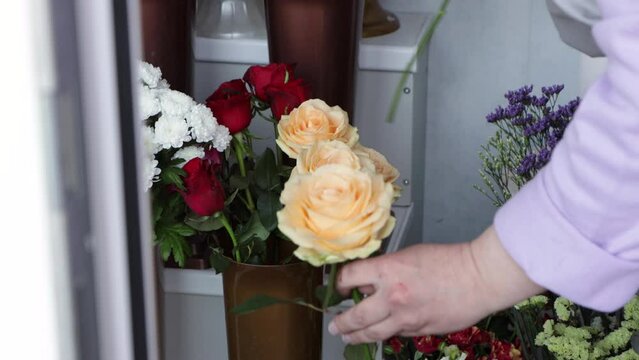 Florist taking yellow roses from vase in street flowers shop. Woman preparing flowers for making bouquet
