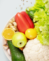 Concept of healthy food and vegan and vegetarian diet. Organic vegetables and fruits, nuts, seeds on a white plate on a blue background. Season food. Flat lay, close up