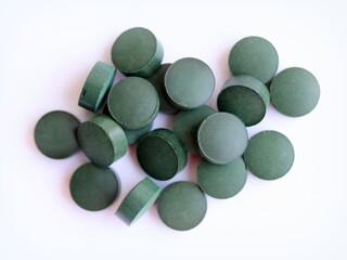 Spirulina pills isolated on white background, close up, top view.