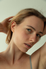 Naklejka premium Portrait of young beautiful woman with light green eyes and blonde hair posing isolated over grey studio backgrouond