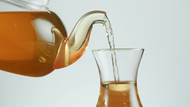 Pouring citrus black tea in armudu glass on white background. Freshly brewed green tea ceremony process, healthy morning, detox drink.