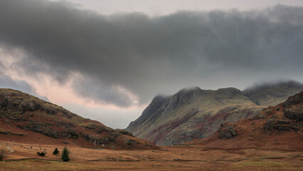 Stunning landscape of dramatic sunrise light over Blea Tarn in Lake District with stunning light