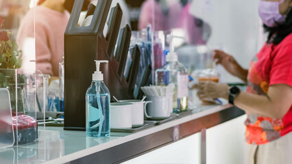 Blue alcohol gel bottle for hand cleaning to prevent the spreading of the Coronavirus (Covid-19) on counter to service for customers at cafe or coffee shop. Healthcare concept. New normal lifestyle.