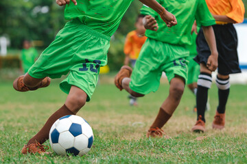 Obraz premium Football soccer children training class. Kindergarten school kids playing football in a field. Group of boys running and kicking soccer on sports grass pitch. Children in sportswear on football match.