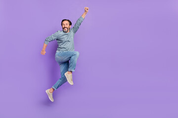 Full body profile side photo of cheerful mature man superhero jump isolated over purple color...