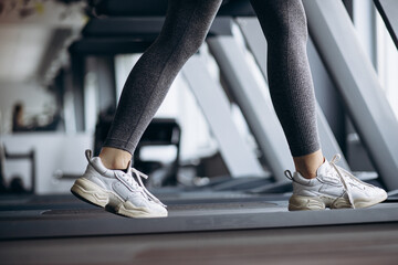 Sporty woman, feet close up running on treadmill at the gym