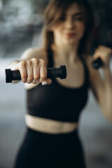 Fototapeta na wymiar Woman lifting dumbbells at the gym
