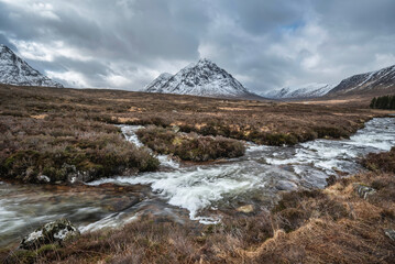 Majestic Winter landscape image of River Etive in foreground with iconic snowcapped Stob Dearg Buachaille Etive Mor mountain in the background