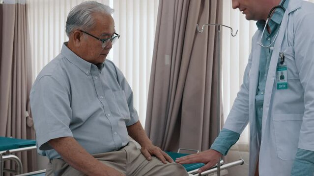 Doctor visit senior male patient on hospital bed while doctor check his pulse. Male physician exam male patient in hospital room. Health medical doctor and life insurance concept.