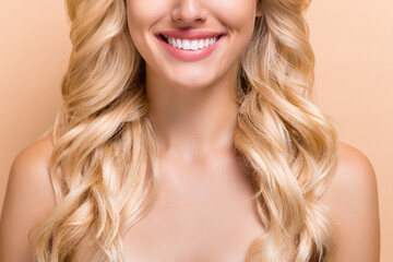 Cropped view portrait of attractive cheerful wavy-haired girl modern aesthetic veneers isolated over beige pastel color background
