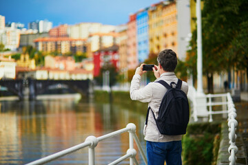 Tourist taking photo of colorful buildings on street of Bilbao, Basque Country, Spain