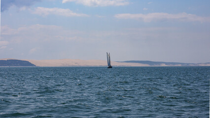 sailboat cruising in front of the Pyla dune, la plus grande dune d'Europe