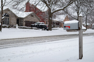 Home Mailbox along a Snow Covered Neighborhood Street with Homes during a Snowfall in Suburban Illinois
