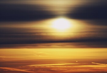 Fototapeta na wymiar Atardecer dorado sobre la ciudad de Madrid en España. El sol tras unas frías nubes de finales de otoño creando un efecto distorsionador sobre la silueta del sol y el horizonte.