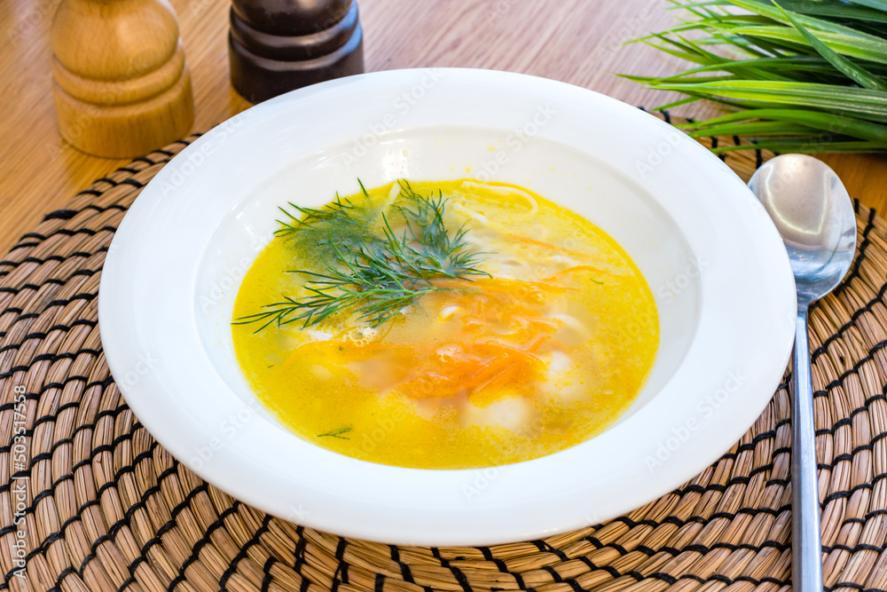 Sticker chicken soup bouillon in a plate on wooden table