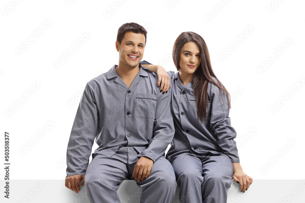 Wall mural Couple wearing same pajamas and sitting on a blank panel