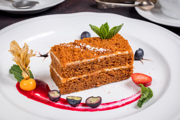 Carrot cake on plate with berries and sauce
