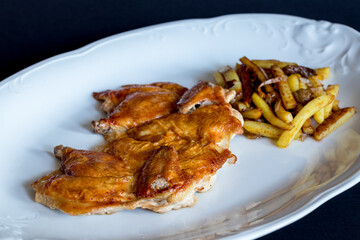 fried chicken tobacco with fried potatoes on white plate on dark table