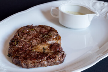 juicy Ribeye steak with pepper sauce on white plate macro close up