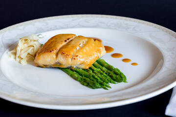 morue grill with asparagus and ginger on white plate on dark table