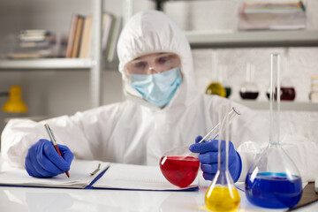 Scientist writing test result and tube liquid reagent. Lab scientist in chemical laboratory