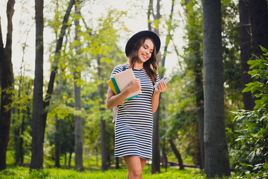 Portrait Of Beautiful Cheerful Schoolgirl Holding Book Using Device Writing Smm Post Pastime On Fresh Air Outdoors