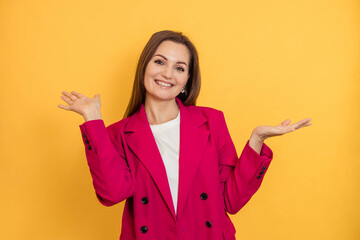 Portrait of a cheerful young woman on a yellow background with her hands raised up