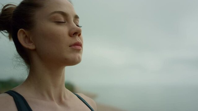Yogi woman making deep breath meditating on beach. Lady practicing yoga close up