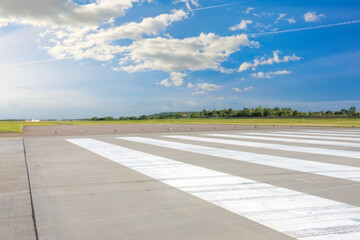 Empty Runway, airstrip in the airport with marking on blue sky with clouds background. Travel aviation concept.