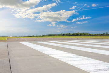 Empty Runway, airstrip in the airport with marking on blue sky with clouds background. Travel aviation concept.