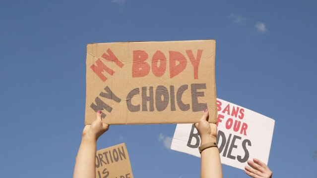 Protesters holding signs My Body My Choice, Abortion Is Healthcare and Bans Off Our Bodies. People with placards supporting abortion rights at protest rally demonstration.