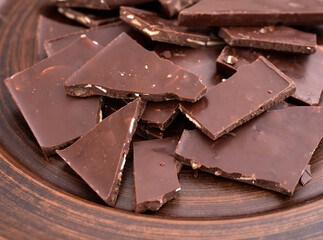 Pieces of broken chocolate on a brown plate.