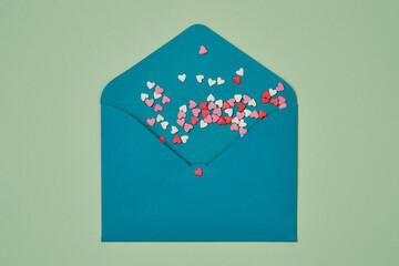 Green congratulatory envelope or letter with candy hearts pastel of color on a green background.