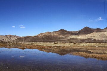 andscape between Tibet to Shigatse  Tibet China.The rock mountains range ,dried grasses reflection in the lake with blue sky