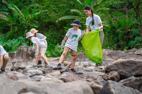 Volunteer Asian and children are collecting plastic bottles that flow through the stream into garbage bags to reduce global warming and environmental pollution. Volunteering and recycling concept.
