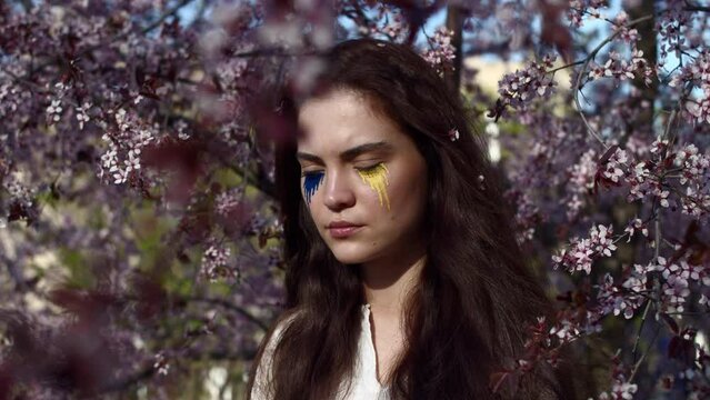 Young attractive girl portrait with Ukrainian flag in the spring cherry garden 