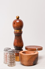 front view of a restaurant salt and pepper shaker and a wood pepper grinder and wood bowl of salt