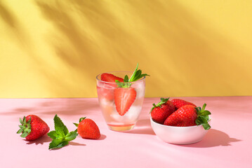 Summer mojito or fruit cocktail with strawberries on yellow and pink background. Strawberry Mojito. Refreshing summer drink with copy space, front view