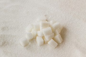 Fototapeta na wymiar White sugar cubes designed on granulated sugar,top view