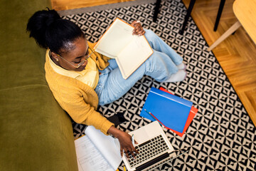 Fototapeta na wymiar Young African American woman sitting on floor at home working. 