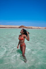Egyptian woman on the beach in Hurghada, Orange Bay, wearing a red bikini in the Red Sea.