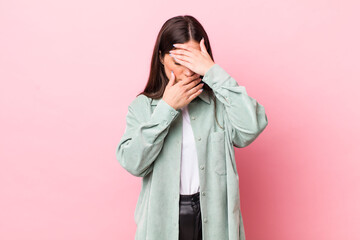 young pretty woman covering face with both hands saying no to the camera! refusing pictures or...