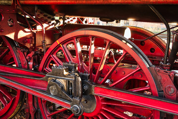 Detail picture of a steam locomotive drive train with big red wheels and brakes. Powerful, historic technology. 