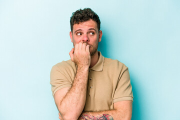 Naklejka premium Young caucasian man isolated on blue background biting fingernails, nervous and very anxious.