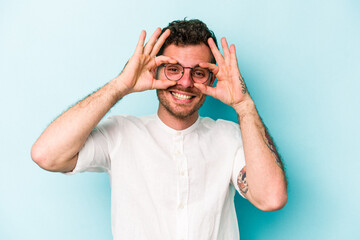 Young caucasian man isolated on blue background excited keeping ok gesture on eye.