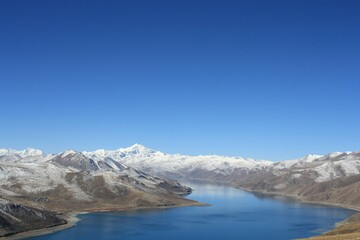 snow covered mountains Landscape of yamdrok   tso lake surround with snow capped mountains and bright blue sky Tibet China. the freshwater lake in Tibet