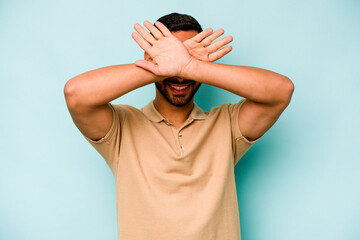 Young hispanic man isolated on blue background keeping two arms crossed, denial concept.